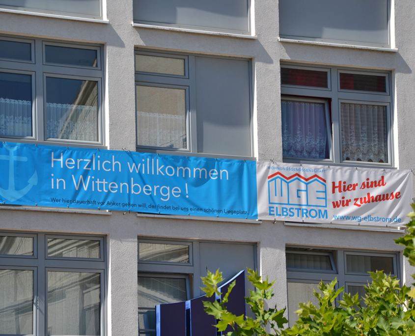 Theaterarkaden Hausansicht mit einem Banner und der Aufschrift "Herzlich Willkommen in Wittenberge" sowie dem WG Elbstrom Logo
